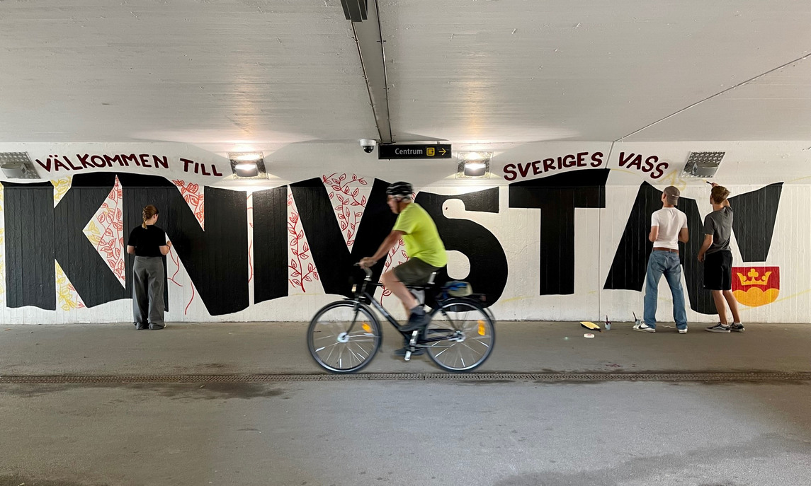 Ungdomar som målar i en tunnel, en cyklist cyklar förbi