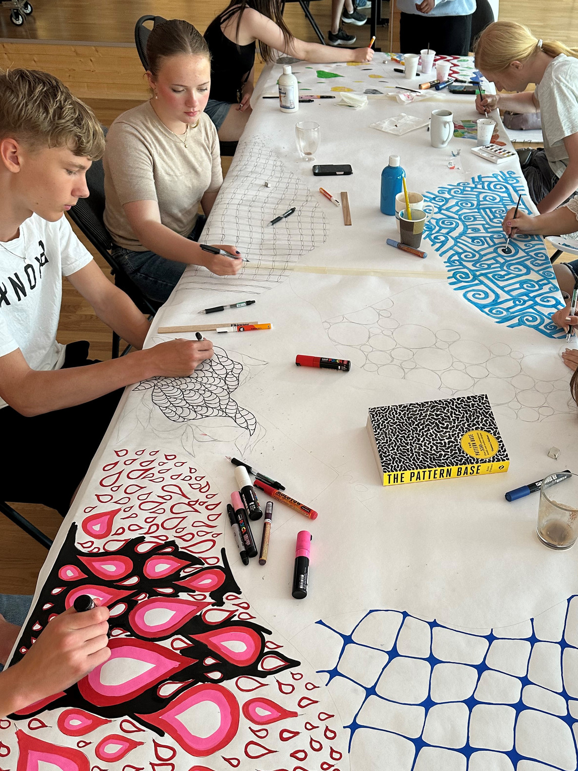 Ungdomar sitter och skissar på mönster vid ett bord